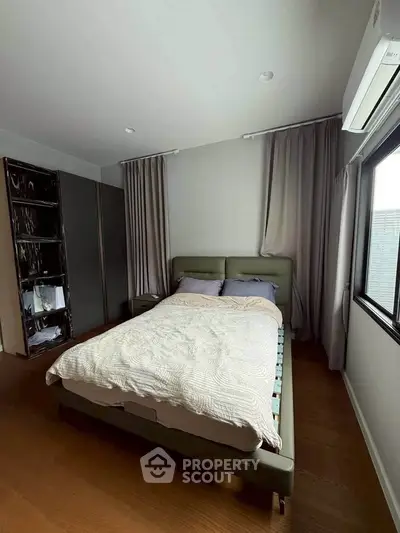 Cozy bedroom with modern decor, featuring a comfortable bed and ample natural light from large window.