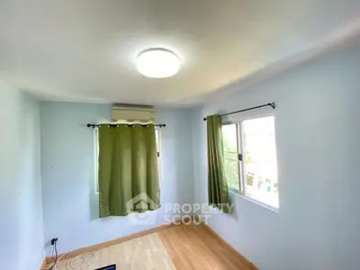 Bright and airy bedroom with wooden flooring and large windows.