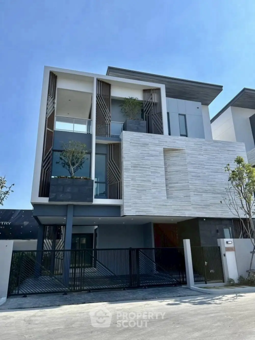 Modern three-story house with sleek design and large windows in a suburban neighborhood.