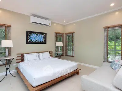 Spacious bedroom with modern decor and large windows offering natural light.