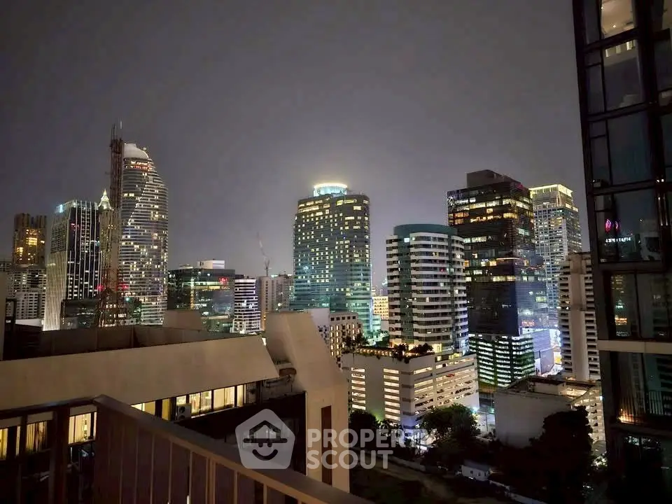 Stunning city skyline view from a high-rise balcony at night, showcasing vibrant urban lights.