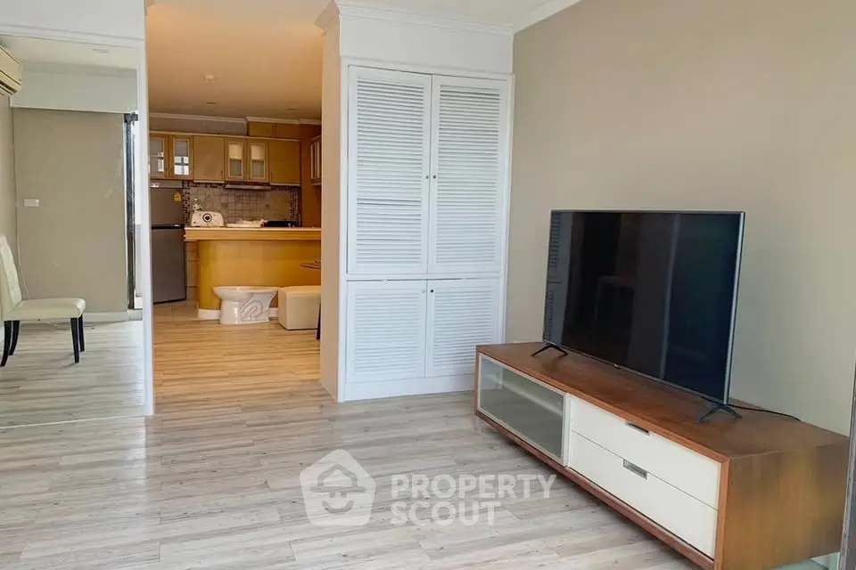 Spacious living room with modern TV setup and open kitchen layout