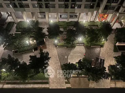 Stunning nighttime view of modern apartment complex courtyard with lush greenery and ambient lighting.