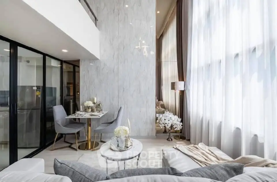 Luxurious modern living room with high ceilings and elegant decor, featuring large windows and stylish furniture.