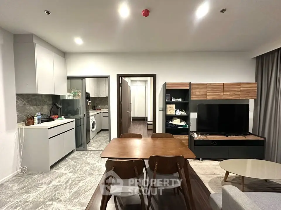 Modern open-plan living room with sleek kitchen and dining area, featuring contemporary furniture and stylish decor.