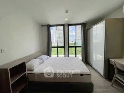 Modern bedroom with large window and city view, featuring a comfortable bed and sleek furniture.