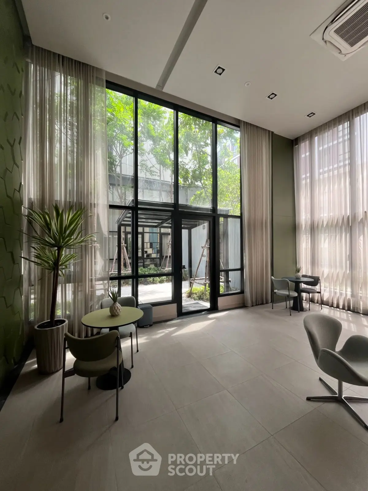 Spacious modern living room with high ceilings and large windows overlooking a garden.