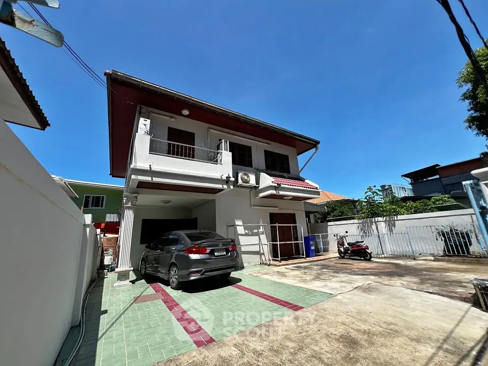 Spacious two-story house with driveway and carport in a sunny residential area.