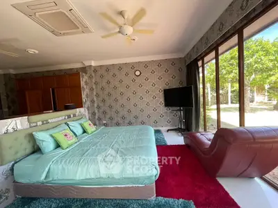 Spacious bedroom with large windows and garden view, featuring modern decor and vibrant accents.