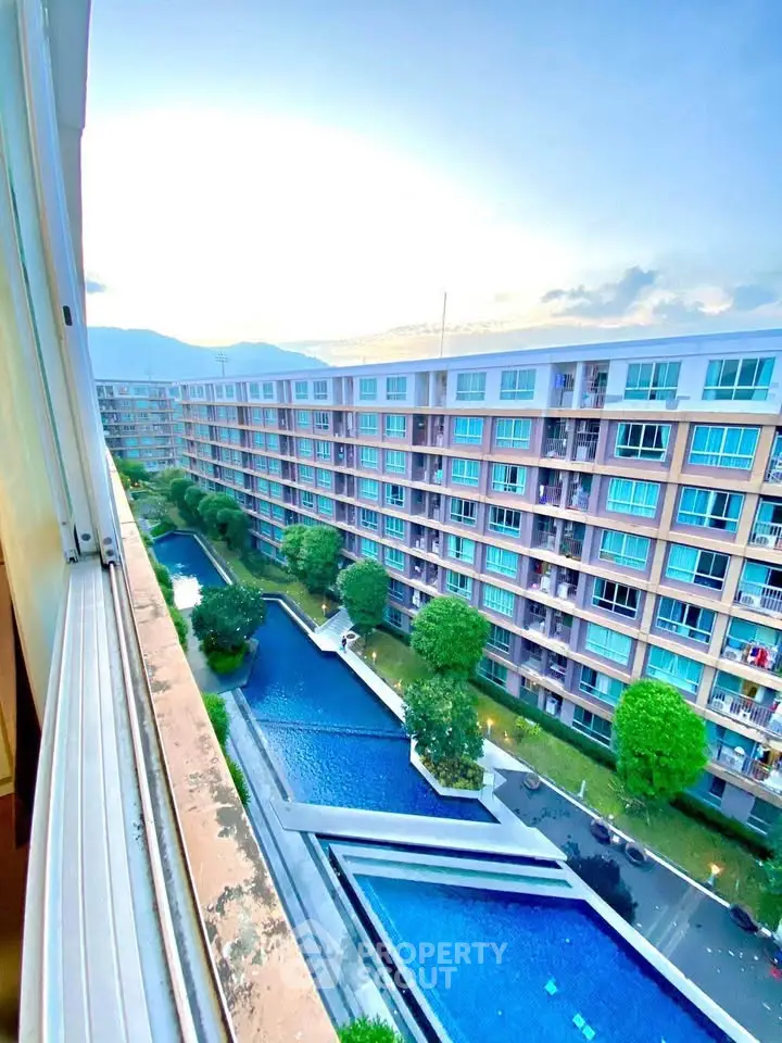 Stunning view of modern apartment complex with pool and lush greenery.