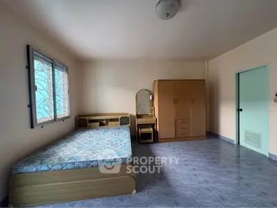 Spacious bedroom with natural light, featuring a bed, wardrobe, and vanity set on tiled flooring.