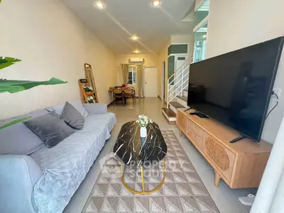 Stylish living room with modern decor and large TV, perfect for relaxation.