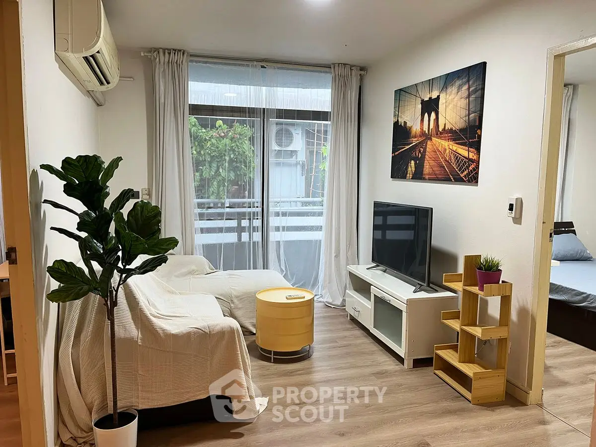 Cozy living room with modern decor and natural light, featuring a TV and stylish furniture.