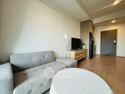 Modern living room with stylish gray sofa and wooden TV stand in a cozy apartment.