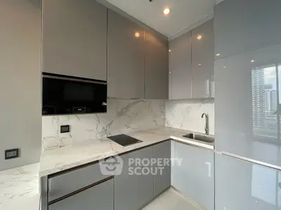 Modern kitchen with sleek grey cabinets and marble countertops in high-rise apartment.