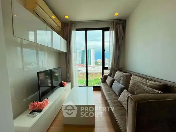 Modern living room with large window and city view, featuring sleek furniture and air conditioning.