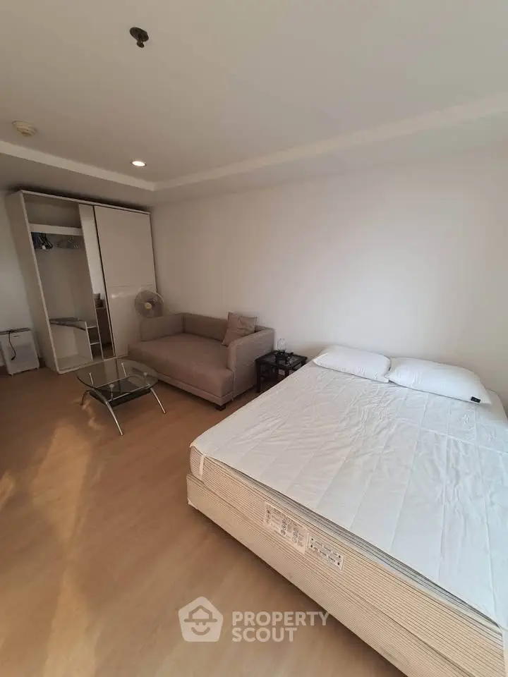 Spacious bedroom with cozy sofa and modern wardrobe in a bright apartment.