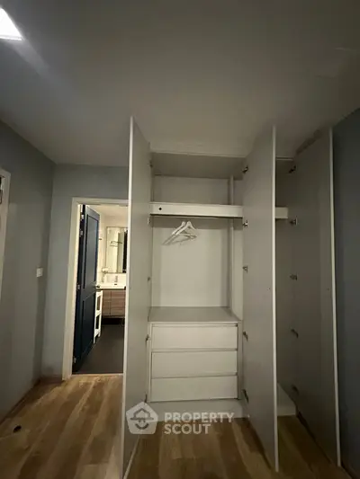 Spacious bedroom with open wardrobe and view into modern bathroom