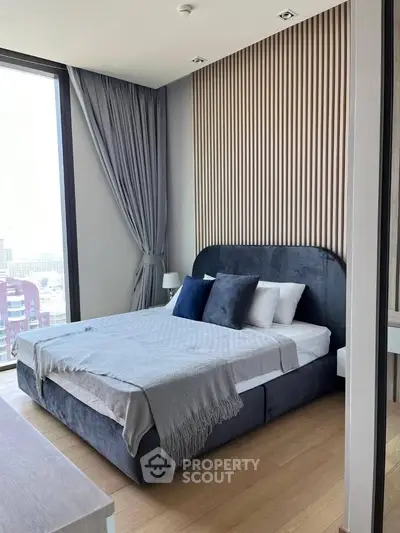 Modern bedroom with stylish decor and large window offering city views