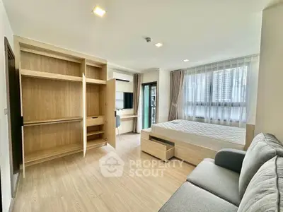 Modern studio apartment with open layout, featuring a cozy bed, stylish sofa, and ample natural light.