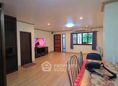 Spacious living room with wooden flooring and modern decor, featuring a large window and stylish furniture.
