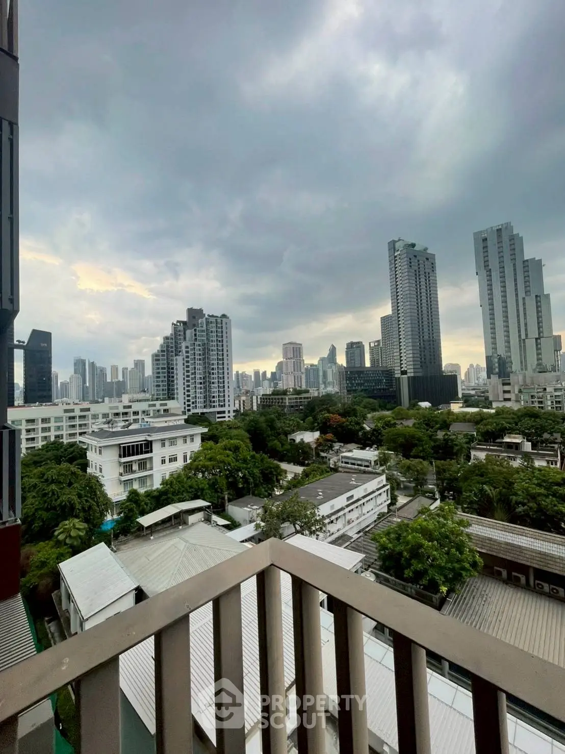 Stunning cityscape view from a high-rise balcony overlooking urban skyline and lush greenery.
