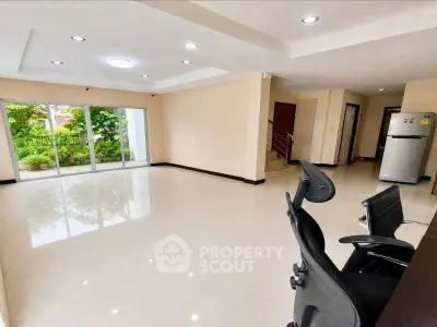 Spacious open-plan living room with garden view and modern office chair.