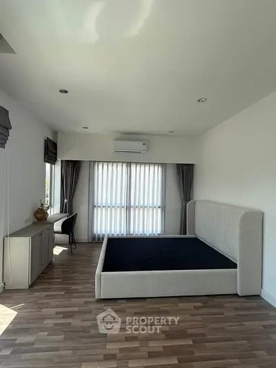 Spacious bedroom with modern design, featuring large windows and elegant furnishings.