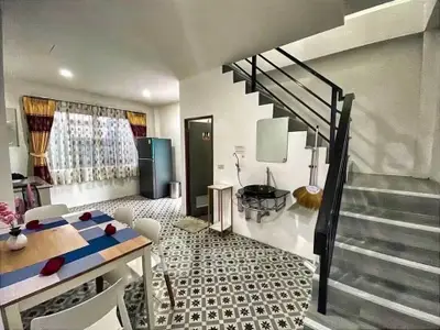 Charming open-layout kitchen and dining area with modern staircase and stylish tile flooring.