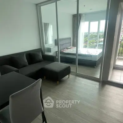 Modern apartment with open living room and bedroom, featuring large windows and a balcony view.