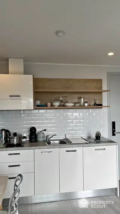 Sleek modern kitchen with white cabinetry, subway tile backsplash, and wooden accents offering a chic culinary space.