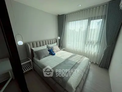 Cozy modern bedroom with plush bed and large window, perfect for relaxation and comfort.