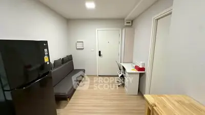 Modern apartment interior with sleek black fridge and cozy seating area.