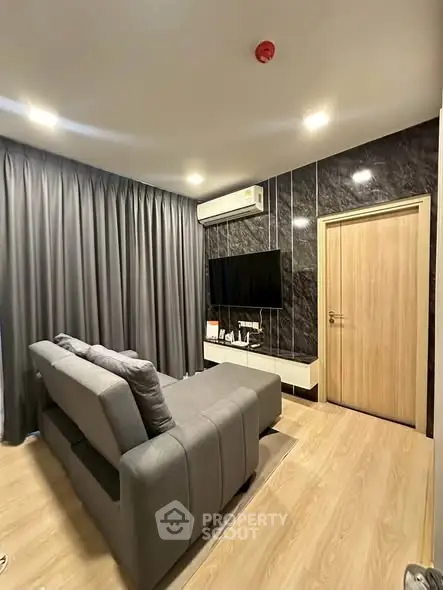 Modern living room with sleek design, featuring a comfortable sofa, wall-mounted TV, and elegant wood flooring.