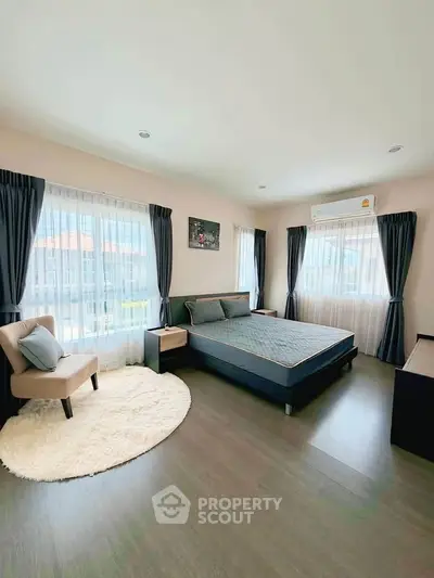 Spacious bedroom with modern furnishings and large windows for natural light.