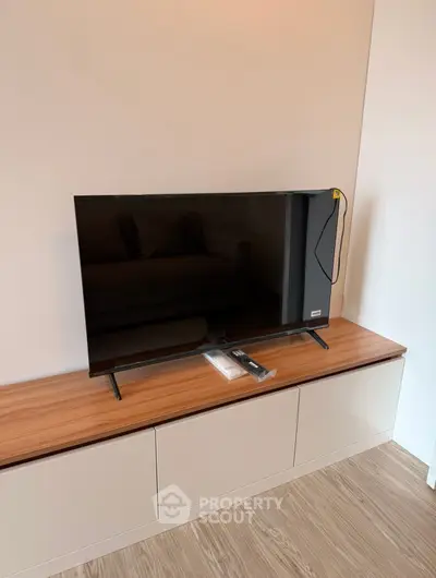 Modern living room with sleek TV on stylish wooden cabinet, perfect for entertainment setup.