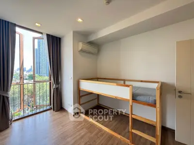 Bright bedroom with loft bed and city view from balcony.