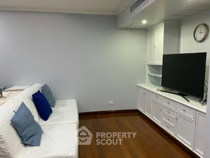 Cozy living room with white sofa, wooden floor, and large TV unit