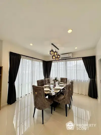 Elegant dining room with modern chandelier and plush chairs in a bright, airy space.