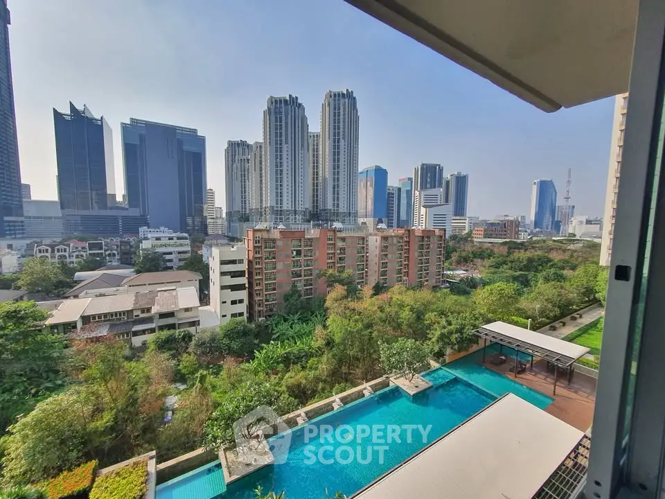 Stunning cityscape view from high-rise apartment with pool and lush greenery.