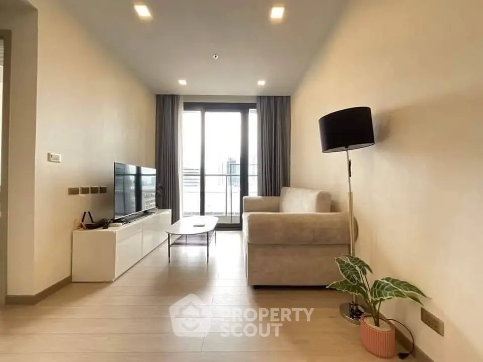 Modern living room with cozy sofa, sleek TV stand, and large window offering city views.