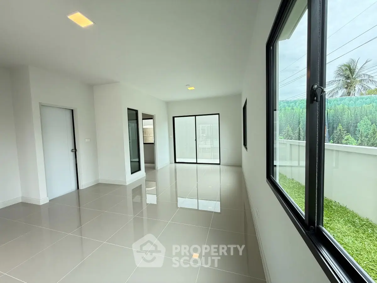 Spacious modern living room with large windows and glossy tiled floors.