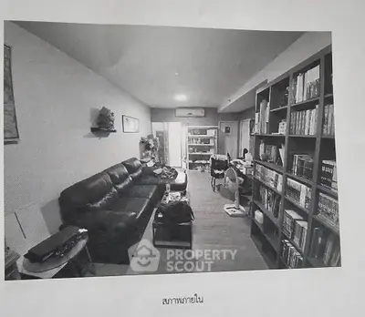 Spacious living room with leather sofa and extensive bookshelf, perfect for relaxation and reading.