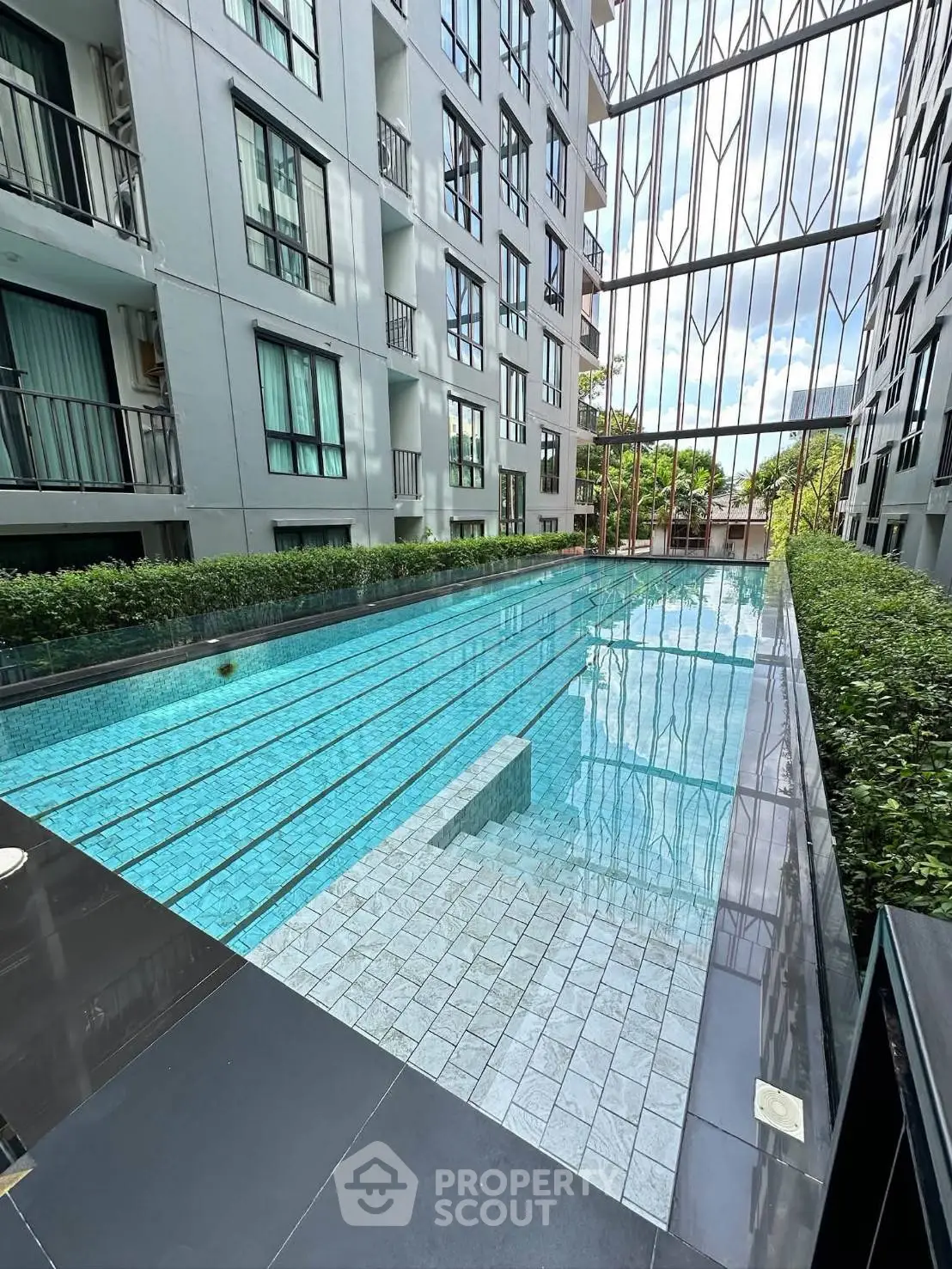 Modern condominium with a sleek outdoor swimming pool and lush greenery, perfect for urban living.
