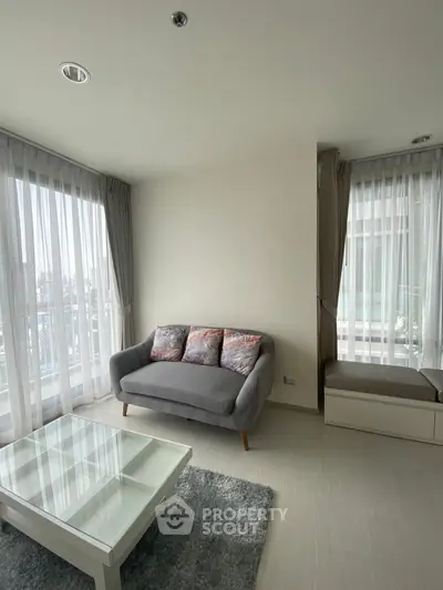 Bright and cozy living room with modern furniture and large windows offering city views.