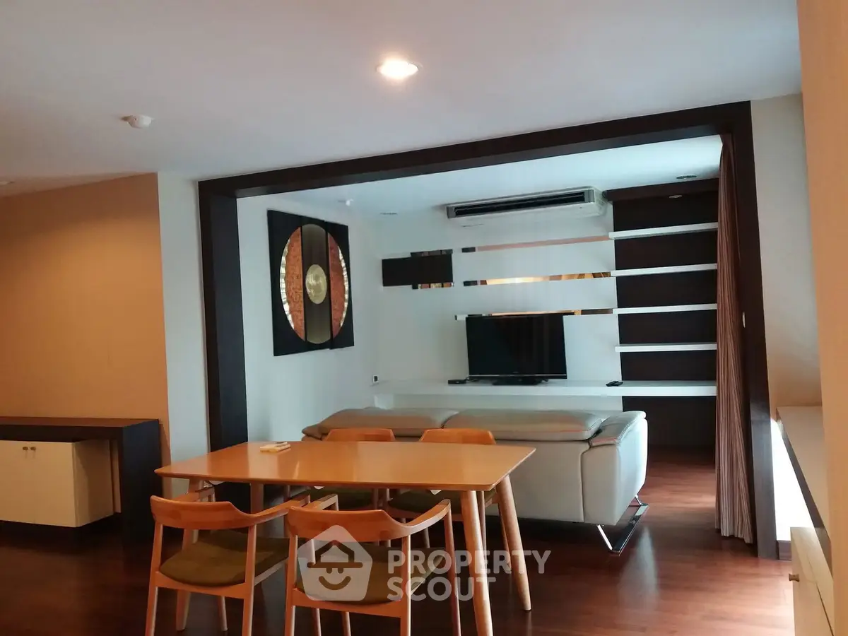 Modern living room with stylish decor and open dining area, featuring sleek furniture and contemporary design.