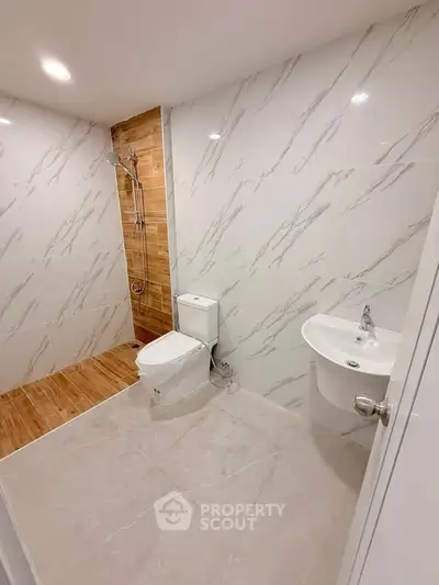 Modern bathroom with sleek design, featuring a shower, toilet, and stylish sink in a contemporary setting.