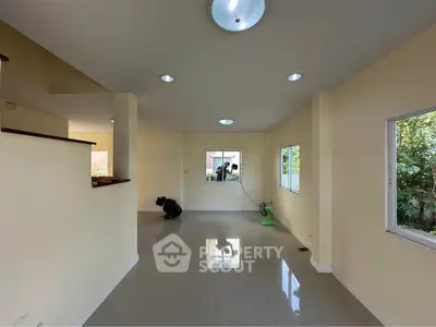 Spacious living room with modern lighting and large windows offering garden views.
