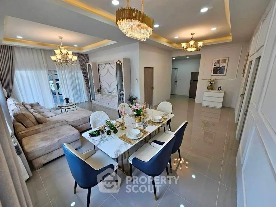 Luxurious open-plan living and dining area with elegant chandelier and modern decor.