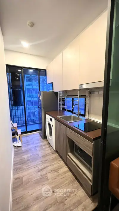 Modern kitchen with sleek appliances and balcony view in urban apartment